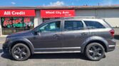 Front of a car dealership with red signs saying 'All Credit' and 'Wheel City Auto' and a gray SUV parked in front.