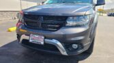 Close-up of a dark gray Dodge SUV parked outdoors, showing front grille and headlights with a Wheel City dealer plate in the foreground.