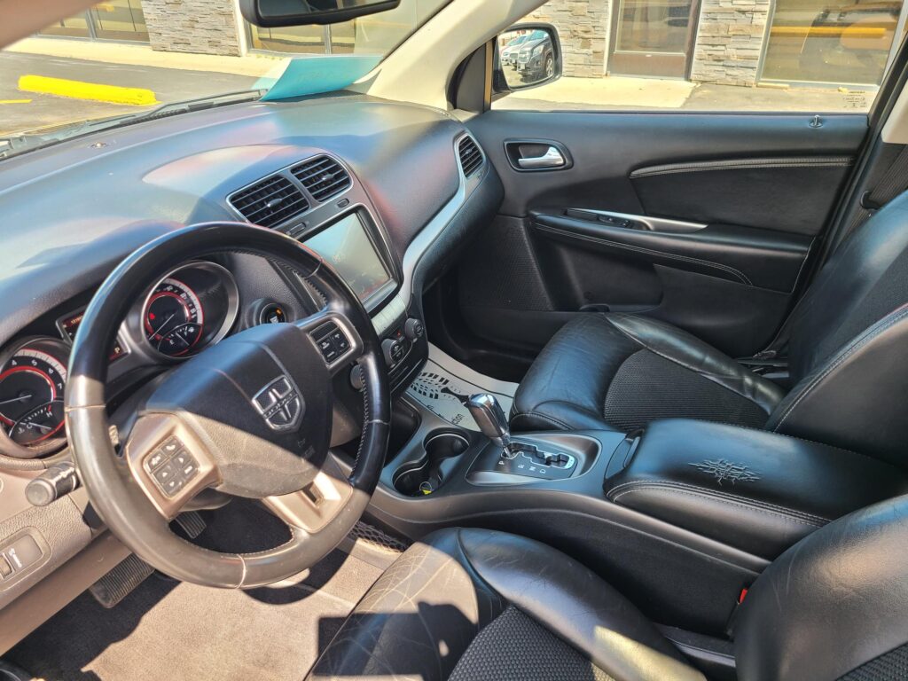 Interior of a car with black leather seats, steering wheel, center touchscreen, and gear shifter visible on the center console.