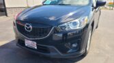 Front view of a dark blue Mazda SUV parked at a dealership, Wheel City plate frame visible in the foreground