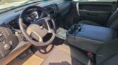 Interior of a Chevrolet pickup: steering wheel, dashboard, and center console with cup holders in view; blue paper on the dashboard