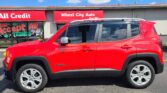 Red Jeep Renegade parked in front of Wheel City Auto storefront under a sunny, blue sky.