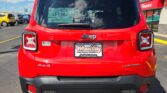Rear view of a red Jeep SUV in a dealership lot, showing tail lights, 4x4 and Limited badges, and a Wheel City Auto Finance Centers plate on the back.