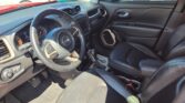 Front interior of a Jeep SUV: black leather seats, steering wheel with Jeep emblem, center console screen, and gear shifter visible in daylight.