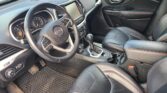 Interior of a black leather Jeep cabin with red contrast stitching, steering wheel, center touchscreen, gear shifter, and front seats visible.