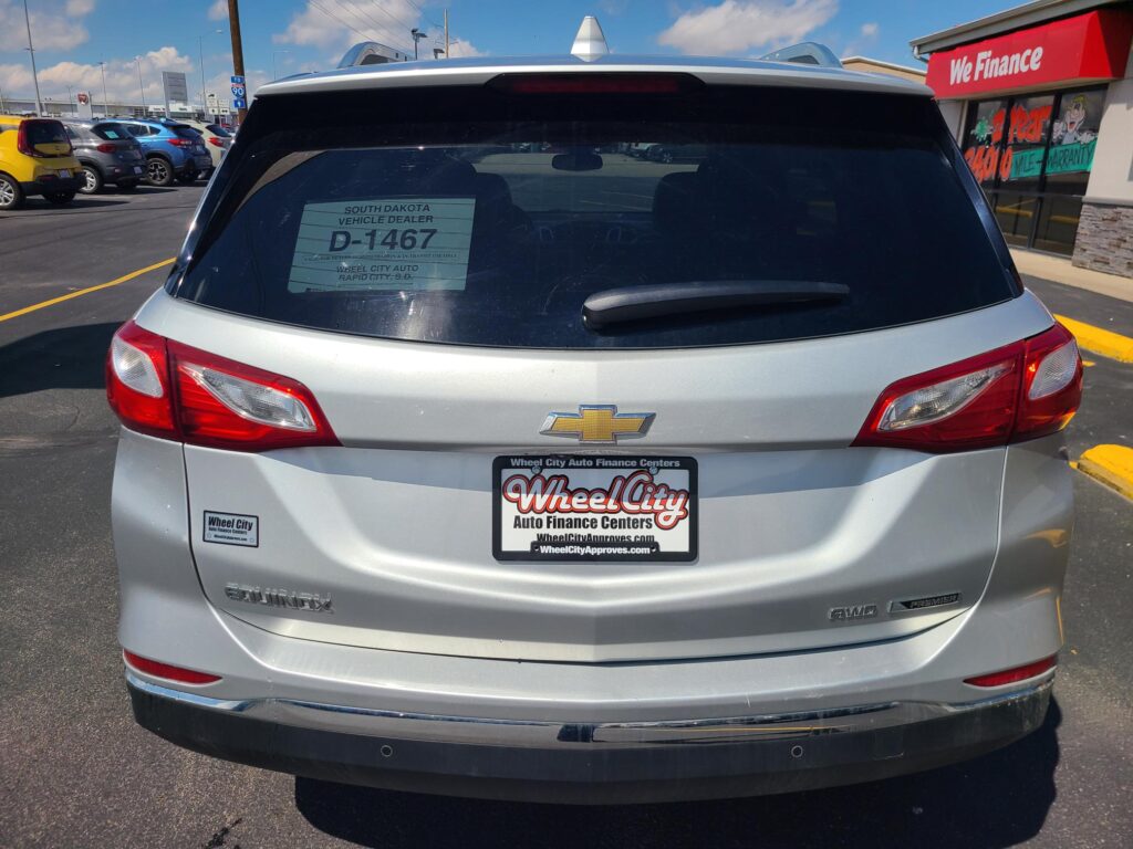 Rear view of a silver Chevrolet SUV in a dealership lot with a D-1467 window sticker on the back window