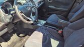 Interior of a Honda car from the driver's side showing the steering wheel, dashboard with controls, gear shifter, and front seats.