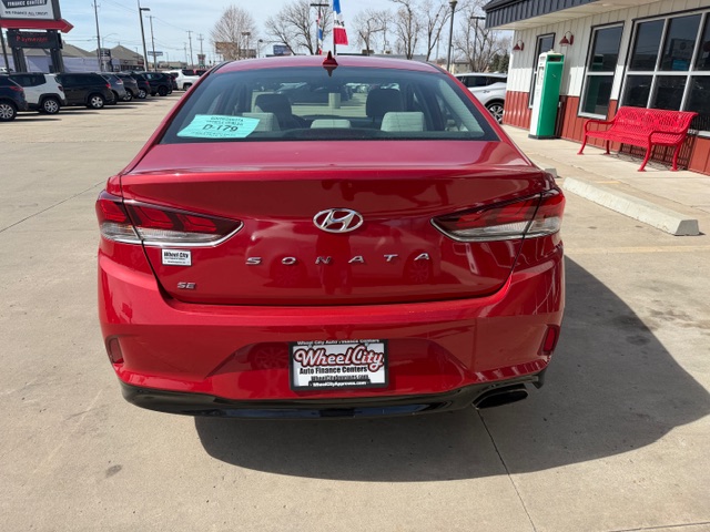 Rear view of a red Hyundai Sonata parked in a dealership lot, showing S E badge and license plate frame reading 'Wheel City'