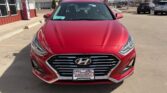 Front view of a red Hyundai sedan parked in a dealership lot with a Wheel City license plate frame.