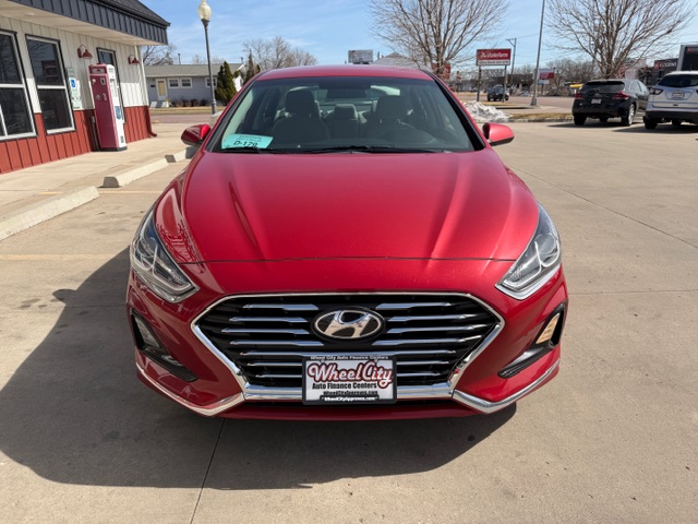 Front view of a red Hyundai sedan parked in a dealership lot with a Wheel City license plate frame.