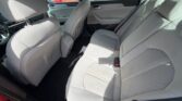 Interior of a red sedan showing light gray rear and front seats with door panels and seat belts visible
