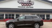 Brown SUV parked in front of Wheel City Auto Finance Centers dealership storefront.
