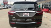 Rear view of a black Buick Enclave SUV at a dealership lot, showing the Buick emblem, Enclave badge, and a Wheel City Auto Finance Centers license plate frame.