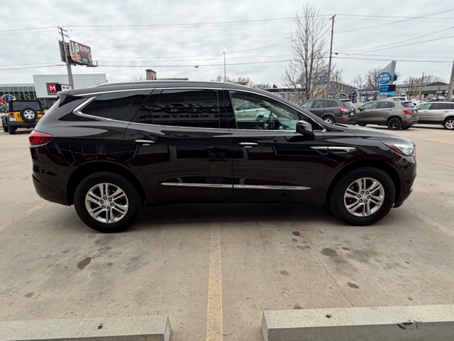 Side view of a black mid-size SUV with chrome trim parked in a dealership lot, with other vehicles and signage in the background.