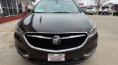 Front view of a dark brown Buick sedan parked at a dealership, with the Buick emblem centered on the chrome grille and a Wheel City plate in the foreground.