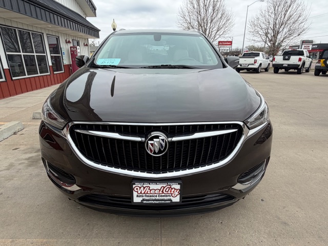 Front view of a dark brown Buick sedan parked at a dealership, with the Buick emblem centered on the chrome grille and a Wheel City plate in the foreground.
