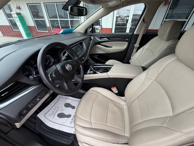 Tan leather front seats in a Nissan SUV, with steering wheel, dashboard, and center console visible; floor mat on the driver side.