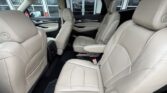 Interior of a beige leather SUV showing front seats and two second-row captain's chairs, with a panoramic sunroof visible above.