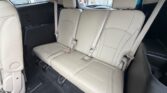 Beige leather rear row of a vehicle with three seating positions and visible seat belts.