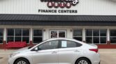 Silver sedan parked in front of Wheel City Auto Finance Centers storefront with large logo sign above the entrance (car dealership scene)