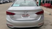 Rear view of a white Hyundai Sonata at a car dealership; blue window sticker on the rear windshield and Wheel City Auto Finance Centers plate.