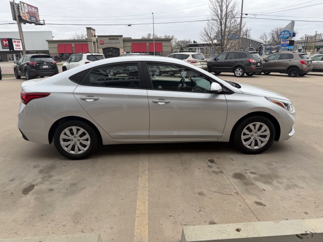 Silver four-door sedan parked in a parking lot, shown in a side profile from the driver's side.