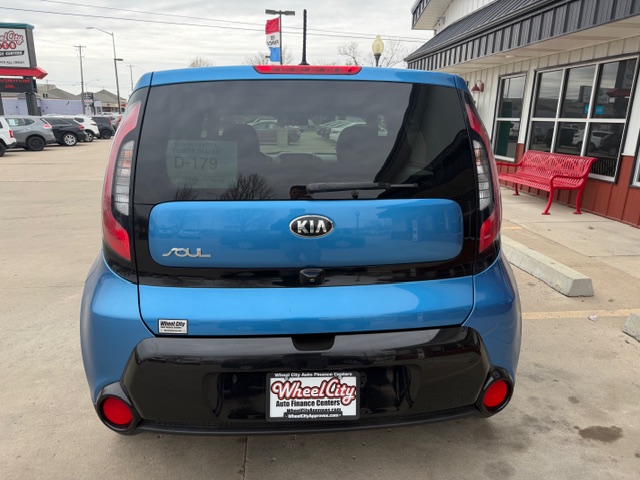Rear view of a blue Kia Soul parked in a dealership lot, showing the Wheel City license plate frame and black lower bumper.