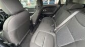 Back seat of a car with three black fabric seats, headrests, and visible seat belts; front seats also shown.