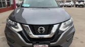 Front view of a gray Nissan SUV at a dealership with a prominent chrome grille and Nissan emblem, license plate frame from Wheel City Auto Finance Centers.