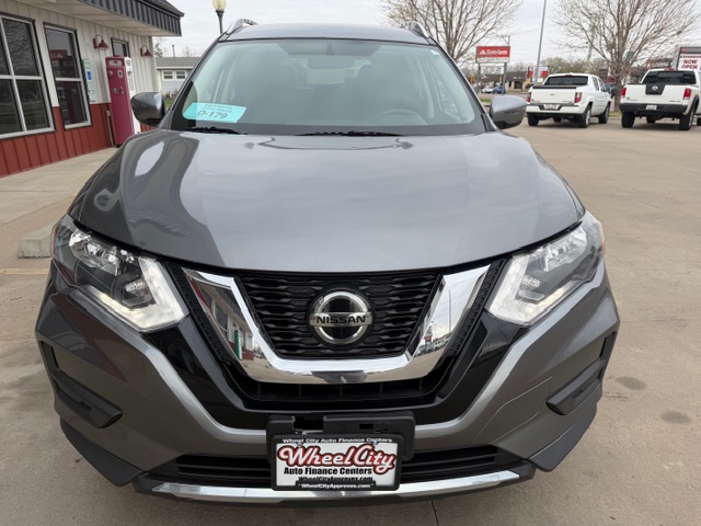 Front view of a gray Nissan SUV at a dealership with a prominent chrome grille and Nissan emblem, license plate frame from Wheel City Auto Finance Centers.