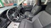 Inside a modern sedan showing the driver's seat and front passenger seat, with a steering wheel, dashboard, and center console including a gear shift; showroom floor mat visible on the floor.