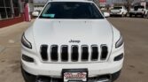 Front view of a white Jeep SUV at a dealership, grille with seven slots and a Wheel City license plate frame visible.