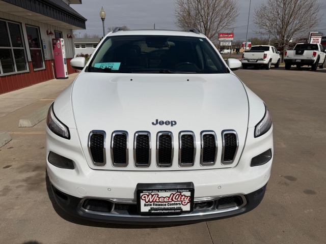 Front view of a white Jeep SUV at a dealership, grille with seven slots and a Wheel City license plate frame visible.