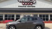 Gray SUV parked in front of Wheel City Auto Finance Centers storefront and sign.