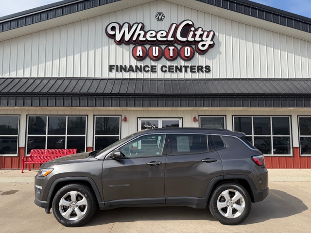 Gray SUV parked in front of Wheel City Auto Finance Centers storefront and sign.