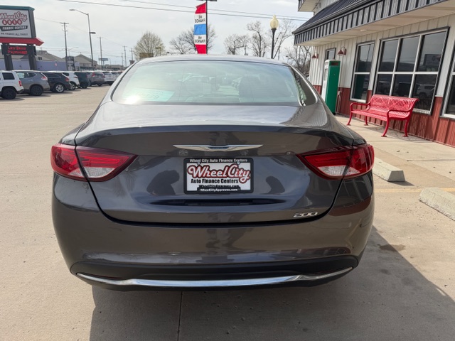 Rear view of a dark gray Chrysler 200 sedan parked at a dealership, with a Wheel City Auto Finance Center license plate frame visible on the trunk.