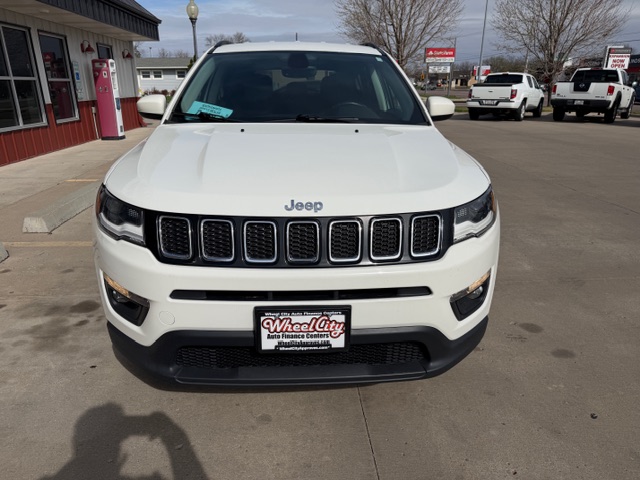 Front view of a white Jeep SUV parked at a car dealership, with a Wheel City Auto Finance Centers license plate frame visible on the front bumper.