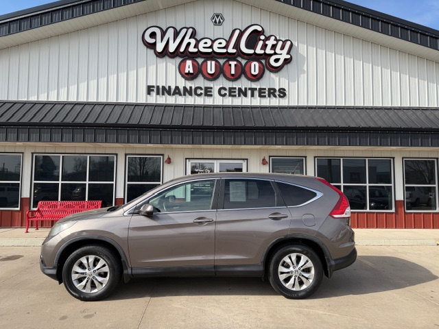 Gray SUV parked in front of Wheel City Auto Finance Centers storefront with red bench nearby