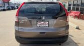 Rear view of a brown Honda CR-V at a dealership with Wheel City Auto Finance Center license plate frame and red benches nearby.