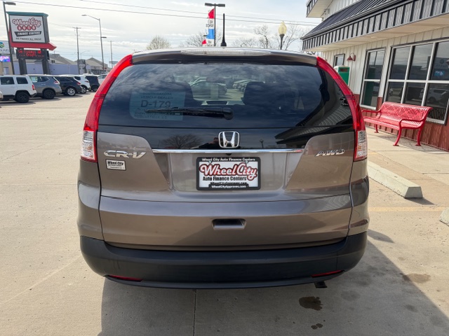 Rear view of a brown Honda CR-V at a dealership with Wheel City Auto Finance Center license plate frame and red benches nearby.