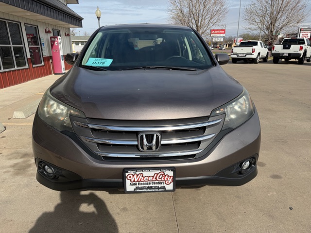 Front view of a brown Honda SUV parked at a car dealership, windshield price tag visible on the left side.