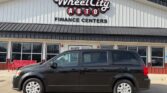 Black minivan parked in front of Wheel City Auto Finance Centers storefront with a large sign above the entrance.