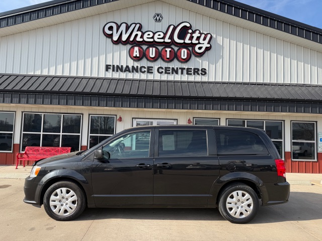 Black minivan parked in front of Wheel City Auto Finance Centers storefront with a large sign above the entrance.