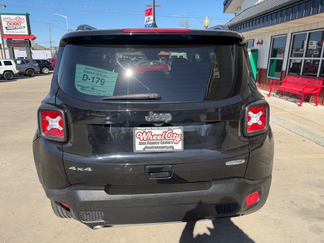 Rear view of a black Jeep 4x4 SUV at a dealership, with a Wheel City license plate frame and a D-179 window sticker.