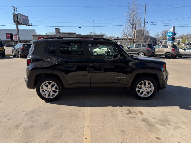 Side view of a black midsize SUV with roof rails parked in a sunny parking lot.