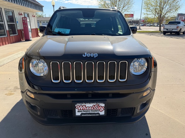 Front view of a dark gray Jeep SUV parked in a dealership lot, showing the seven-slot grille and round headlights; dealer plate reads Wheel City Auto Finance Centers.