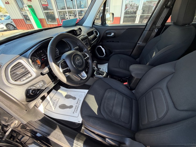 Interior of a dark gray Jeep: front driver and passenger seats, steering wheel, center console with gear shifter, and dashboard viewed from the open driver's side door.