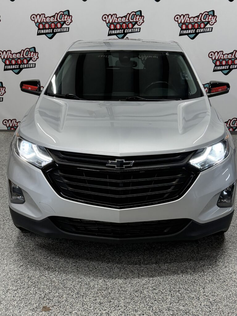 Front view of a silver Chevrolet SUV in a showroom with Wheel City Auto Finance Centers backdrop.