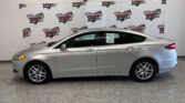 Silver sedan in a dealership showroom with a branded backdrop reading Wheel City Auto Finance Centers.