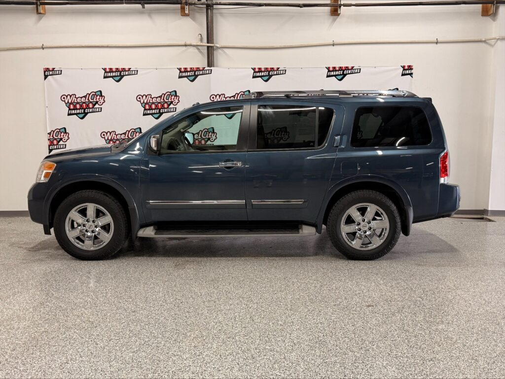 Side view of a blue SUV with chrome wheels parked indoors in front of a Wheel City banner backdrop